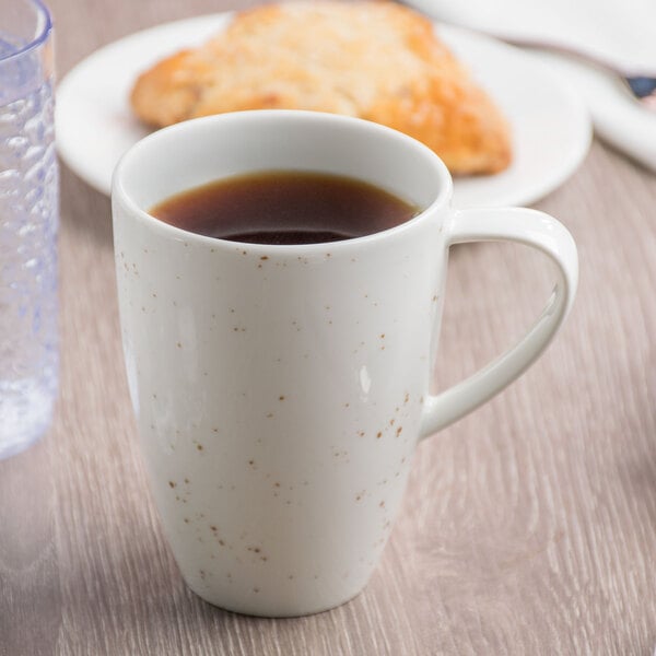 A Schonwald white porcelain mug filled with coffee on a table.