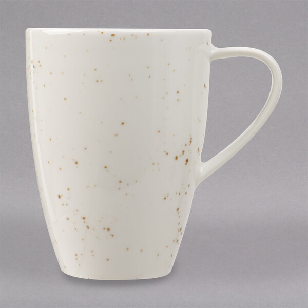 A white Schonwald porcelain mug with brown speckled spots and a unique design on it.