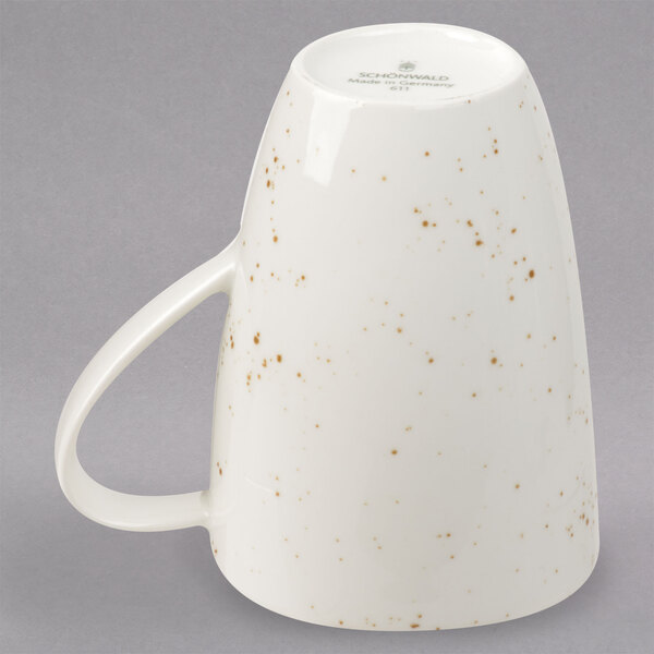 A white Schonwald porcelain mug with brown speckles and a handle.
