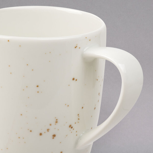 A close up of a white Schonwald porcelain mug with a speckled design.