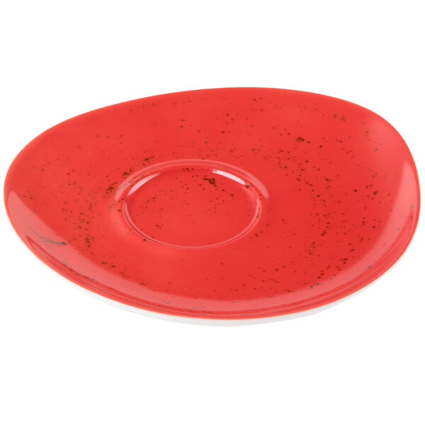 A red porcelain saucer with specks on it.
