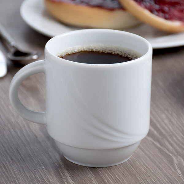 A white Schonwald stacking mug filled with brown liquid on a table.