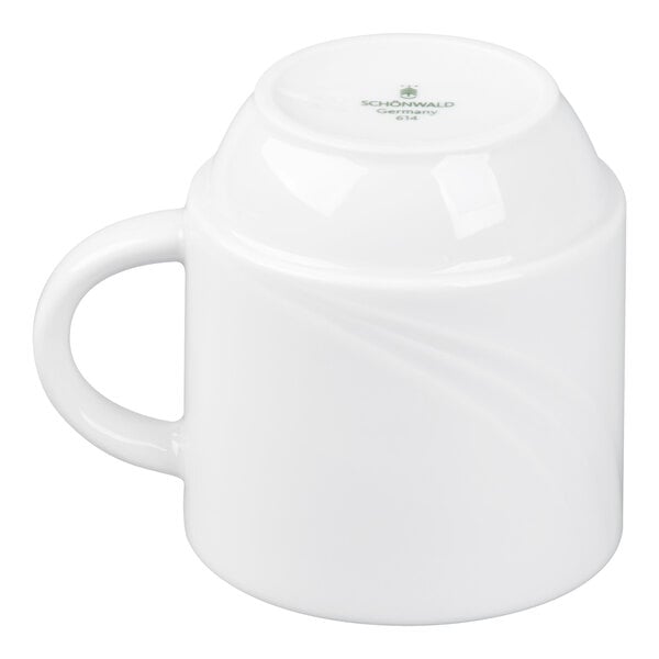 A white porcelain mug is shown upside down with a handle on the left side.