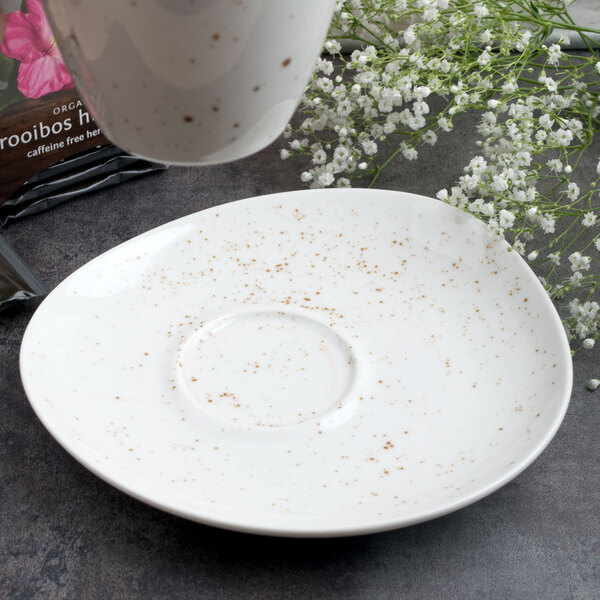 A white Schonwald porcelain saucer with brown speckled spots.