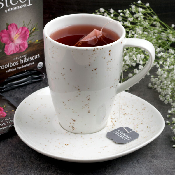 A Schonwald white porcelain saucer with a cup of tea and a tea bag on it.