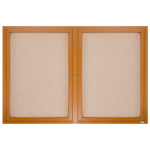 A natural oak framed Aarco enclosed bulletin board with two doors over cork.