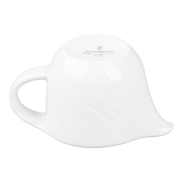 A small white porcelain sauce boat is shown upside down, displaying its handle and spout.