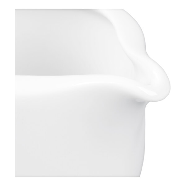 A close-up view of a glossy white porcelain object with a curved edge, likely part of a dish or sauce boat.