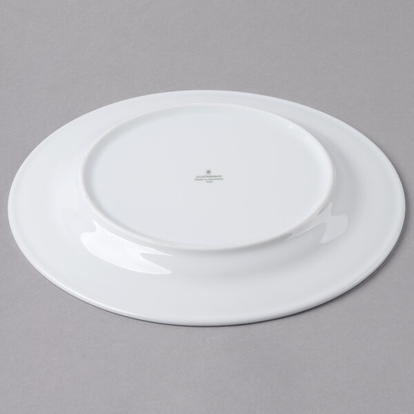 A Schonwald round white porcelain plate with a green logo.