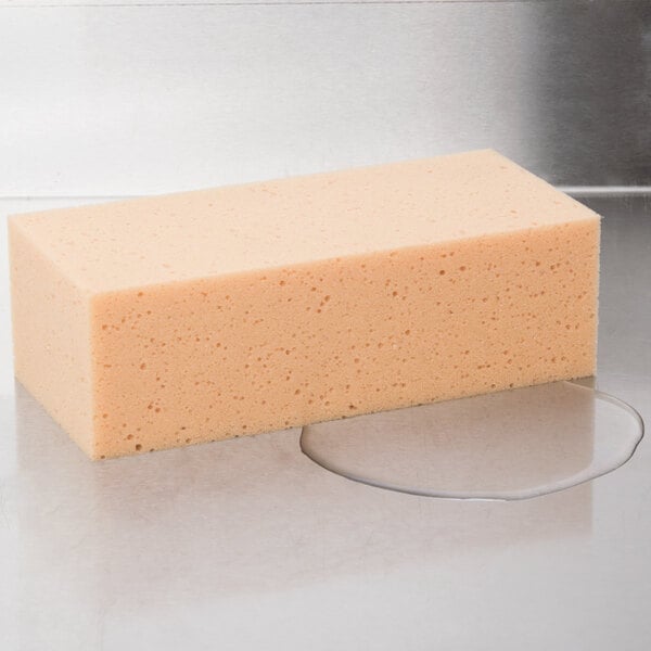 An orange rectangular Unger sponge on a white surface.