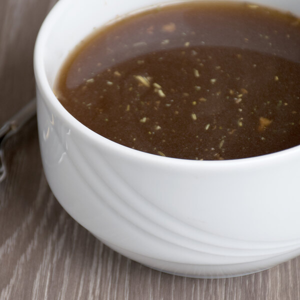 A Schonwald white porcelain bowl filled with brown soup on a wood surface.