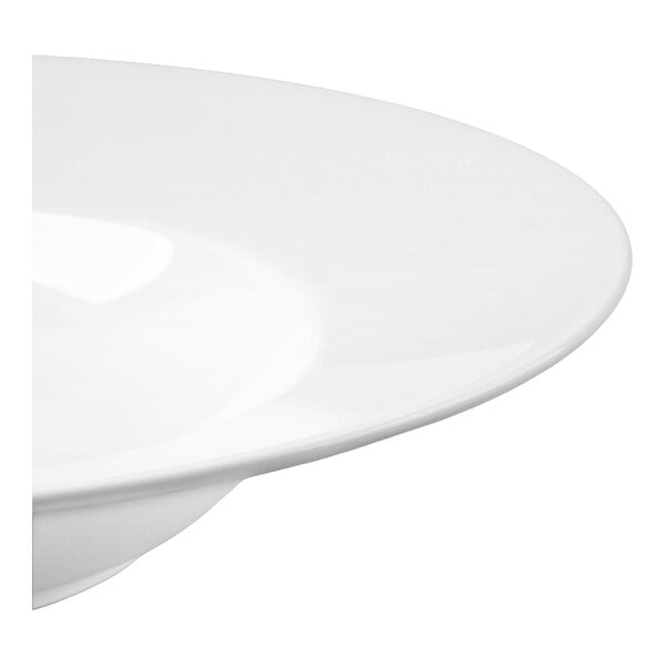 A partial view of a glossy white, round, deep-rimmed bowl.