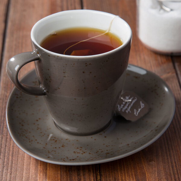 A Schonwald dark gray porcelain cup of tea on a saucer.