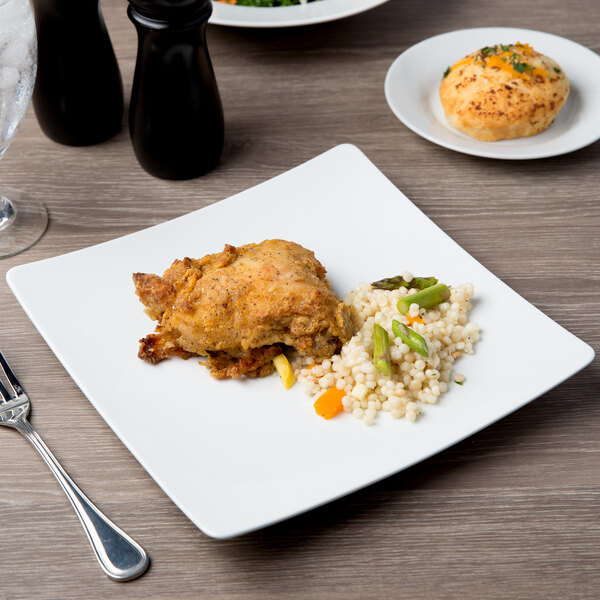 A Schonwald white porcelain coupe plate with rice and vegetables on a table.