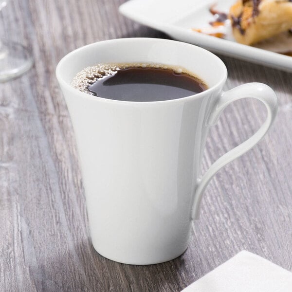 A Schonwald white porcelain cup filled with coffee on a table.