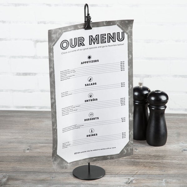 A Clipper Mill black powder coated iron wire table card holder with a menu next to salt and pepper shakers.