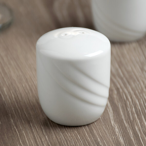 A white Schonwald porcelain salt shaker on a wood table.