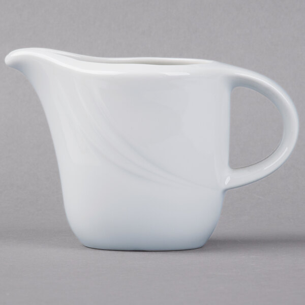 A Schonwald white porcelain creamer with a handle on a white surface.