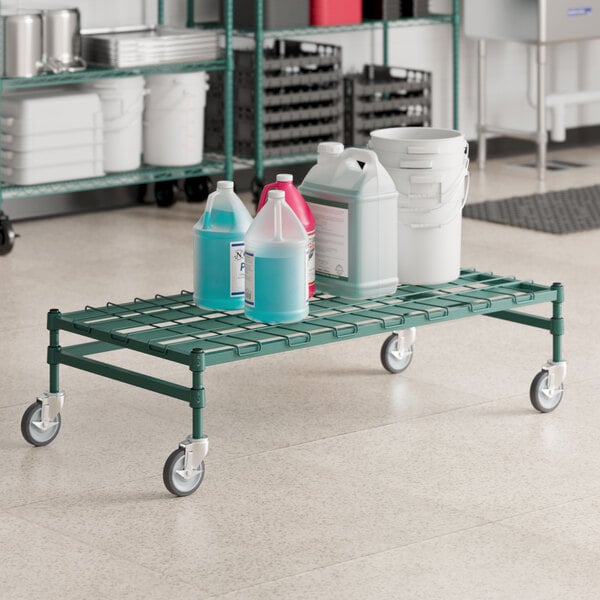 A green metal Regency dunnage cart with bottles and white buckets on it.