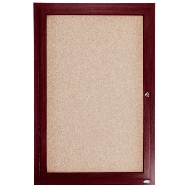 An Aarco enclosed bulletin board with a cherry frame and glass door on a cork board.