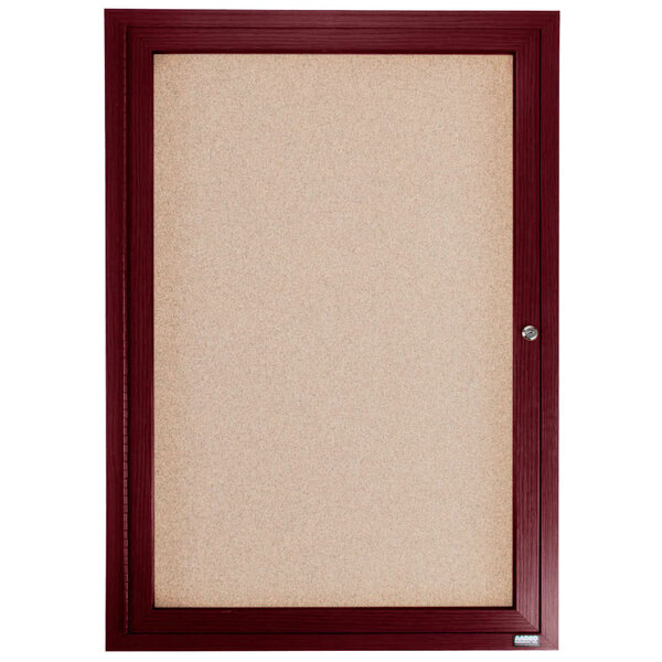 An Aarco cherry frame enclosed bulletin board with a cork board and glass door.