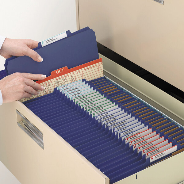 A person opening a file drawer with Smead classification folders.