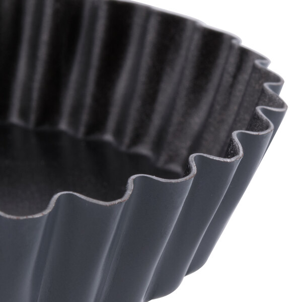 A close-up of a black Matfer Bourgeat fluted tart/quiche pan.