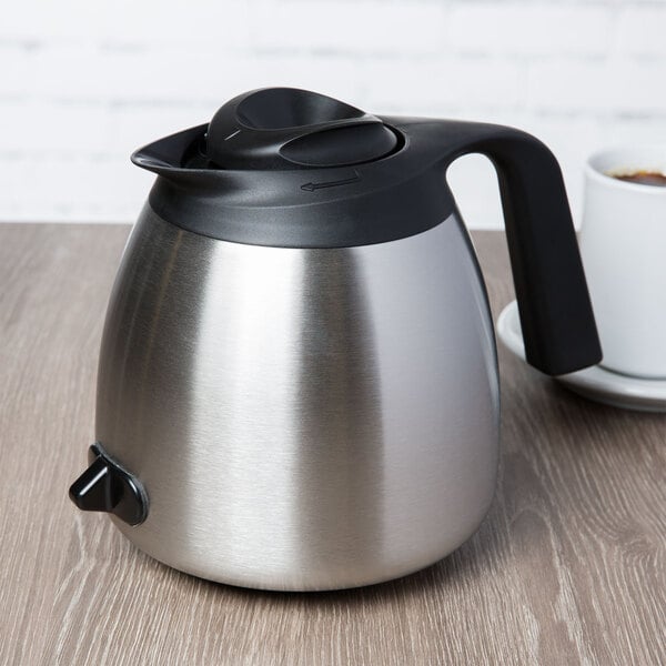 A silver and black Bunn stainless steel thermal carafe on a table.