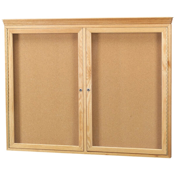 An Aarco natural oak enclosed bulletin board with crown molding.