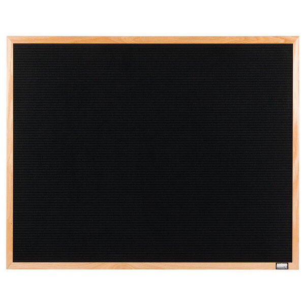 A black Aarco indoor message board with an oak wood frame.