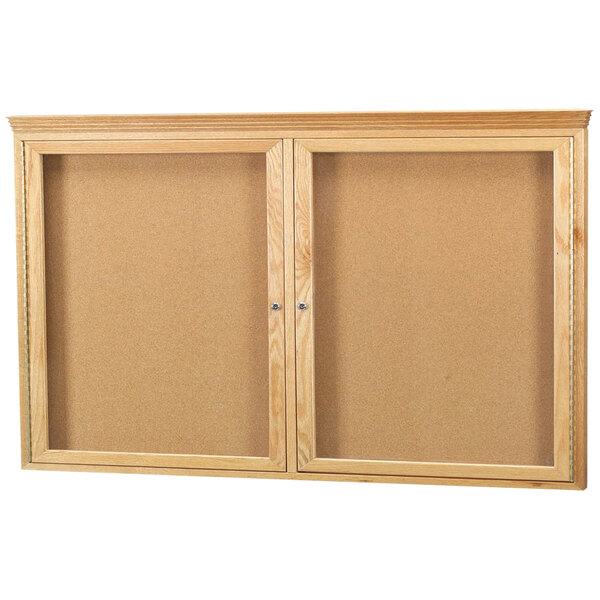 Two Aarco enclosed cork bulletin boards with natural oak frames and glass doors.