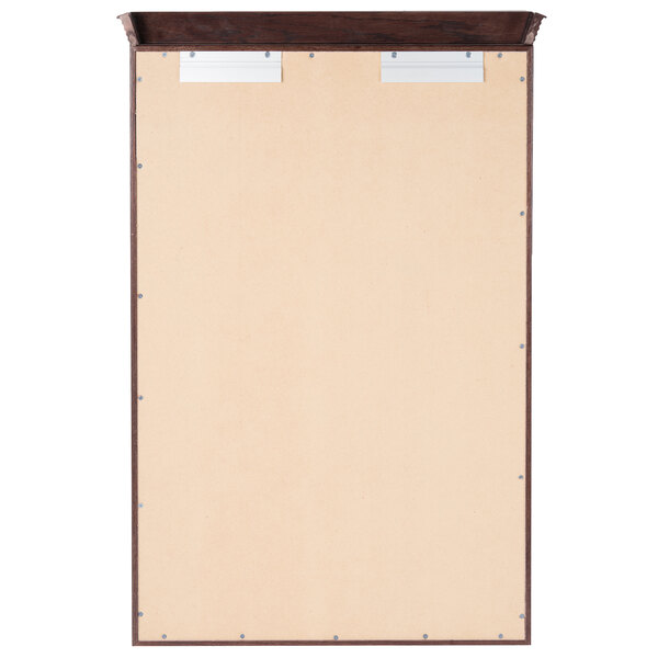 A rectangular wooden bulletin board with a cherry wood frame and crown molding with a metal panel on top.