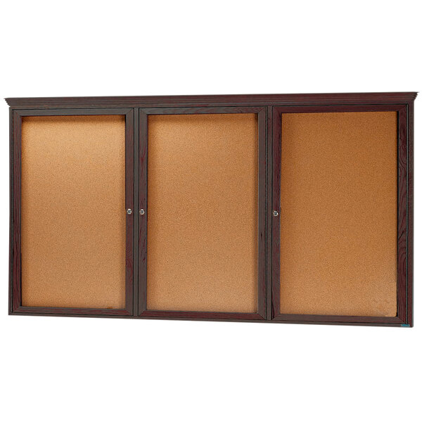 An Aarco walnut cork bulletin board with three doors.