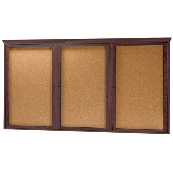 A walnut Aarco cork bulletin board with three hinged glass doors.