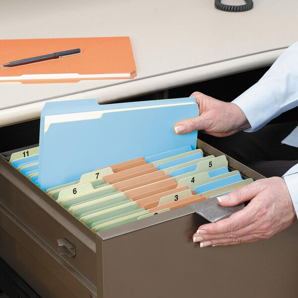 A person holding a Smead file folder with brown and green tabs.
