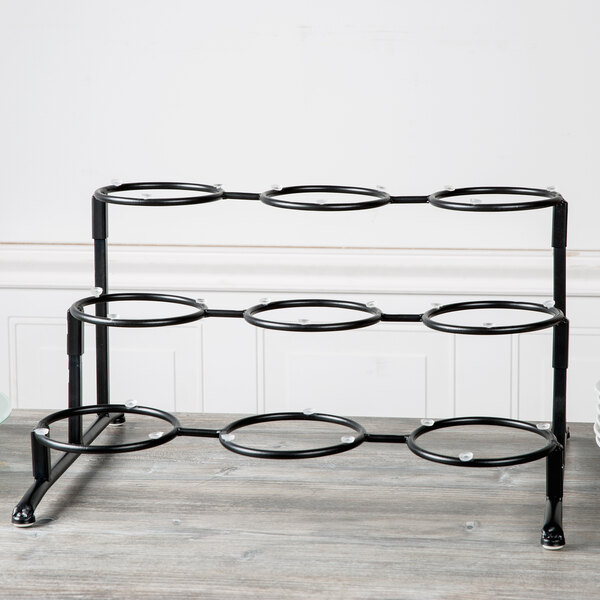 A black metal rack with round black rings holding circular objects.