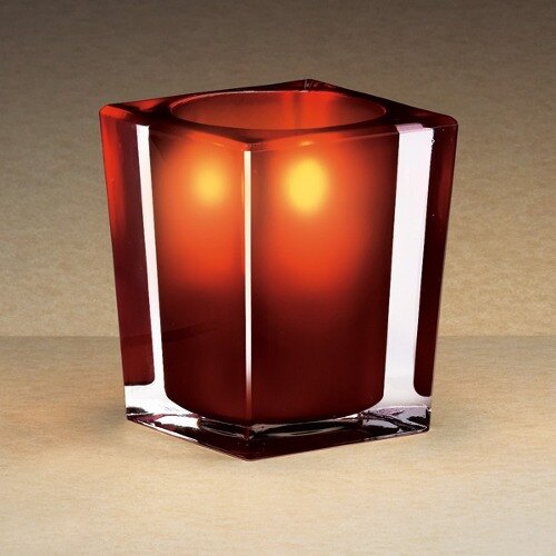 A Sterno square glass candle holder with a red candle inside.