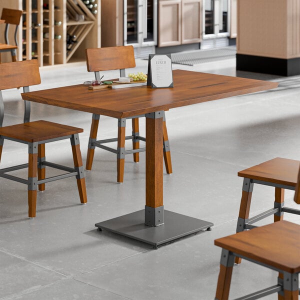 A rectangular solid wood table with a rustic walnut finish and industrial metal accents, surrounded by matching chairs.