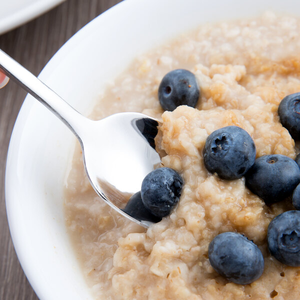 A World Tableware stainless steel teaspoon in a bowl of oatmeal with blueberries.