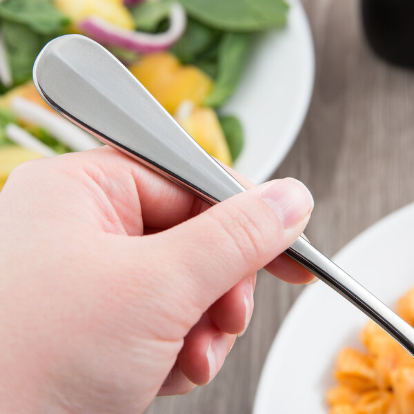 A hand holding a Libbey stainless steel dinner fork.