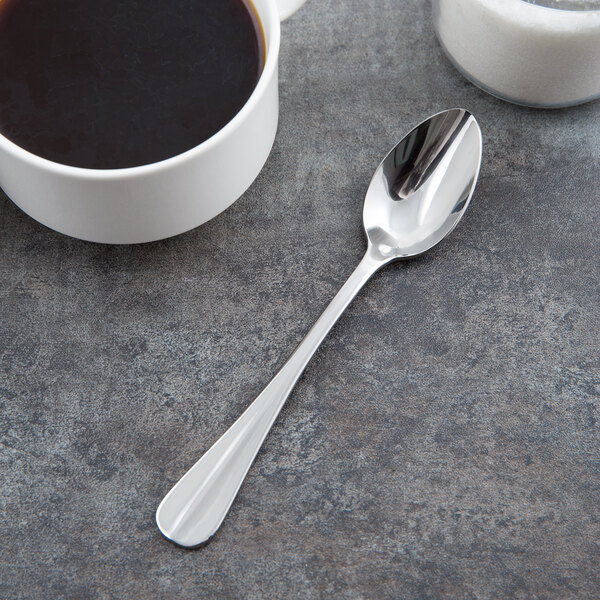 A Libbey stainless steel demitasse spoon in a cup of coffee on a table.