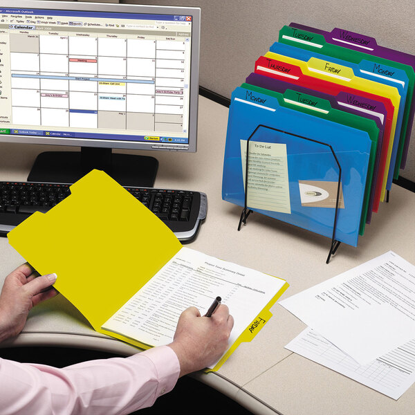 A person writing on a yellow Smead file folder.