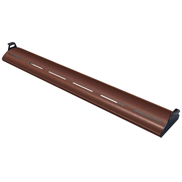 An antique copper Hatco display light with warm lighting on a brown metal shelf.