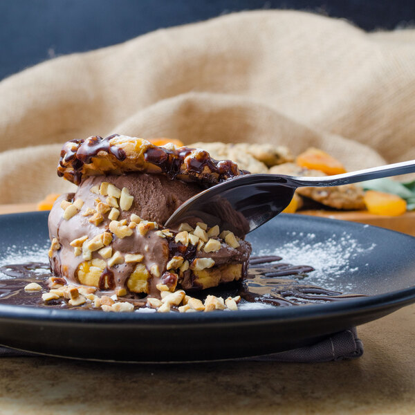A World Tableware Columbus stainless steel dessert spoon with chocolate on it, on a plate of chocolate ice cream.