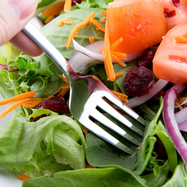 A World Tableware stainless steel salad fork in a salad.