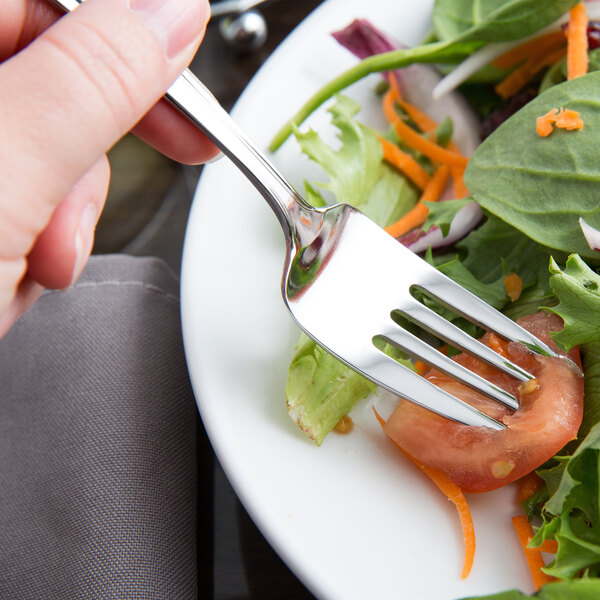 A Libbey stainless steel salad fork on a plate of salad.