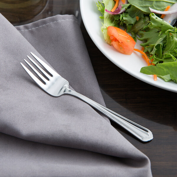 A Libbey stainless steel salad fork on a plate of salad.