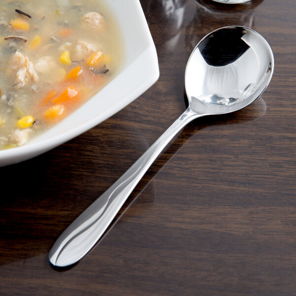 A bowl of soup with a Libbey stainless steel bouillon spoon next to it.