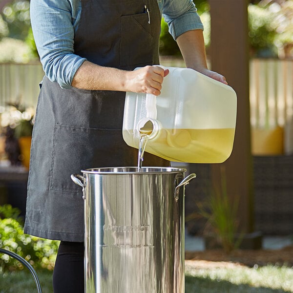 Chef pouring peanut oil into a large stock pot