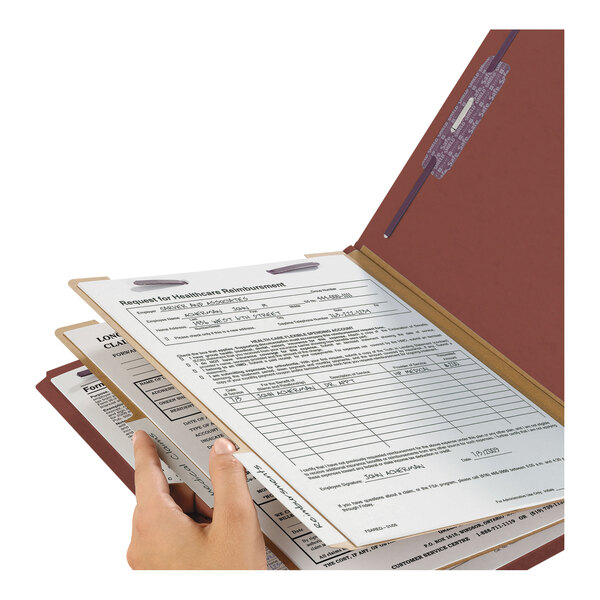A hand holding a Smead SafeSHIELD legal size classification folder with documents.